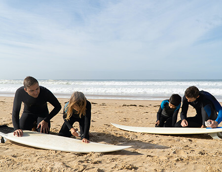 Surfers waxing boards on the beach before a session